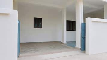 An empty room with a tiled floor, two windows, and a blue door.