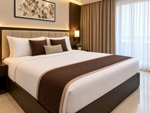 Una cama grande con cabecera, una mesita de noche, una lámpara y una ventana con cortinas.