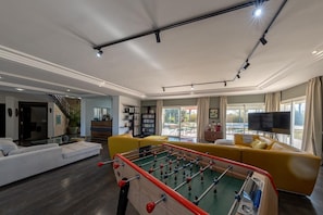 A modern living room with a foosball table, a sofa, a television, and a staircase. - VINEA HOUSE  (Skhirat)
