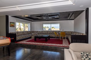 A living room with a patterned sofa, a coffee table, and a foosball table. - VINEA HOUSE  (Skhirat)