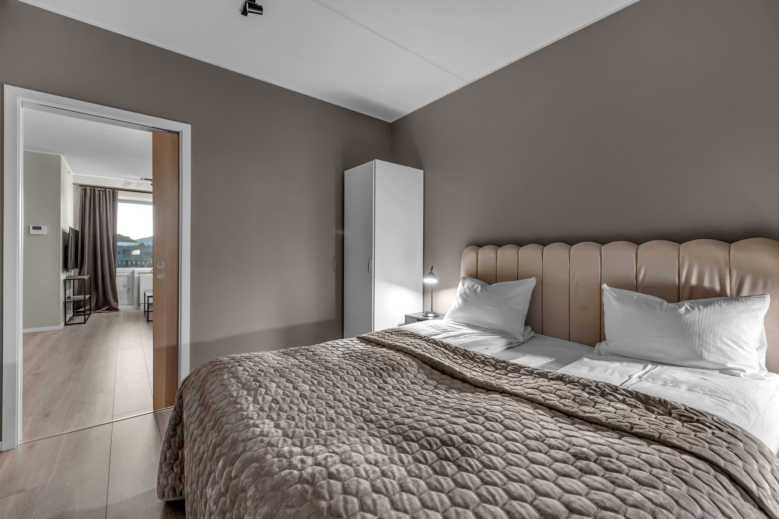 Une chambre moderne avec un grand lit, une armoire et une vue sur l’extérieur.