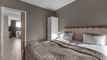 Une chambre moderne avec un grand lit, une armoire et une vue sur l’extérieur.