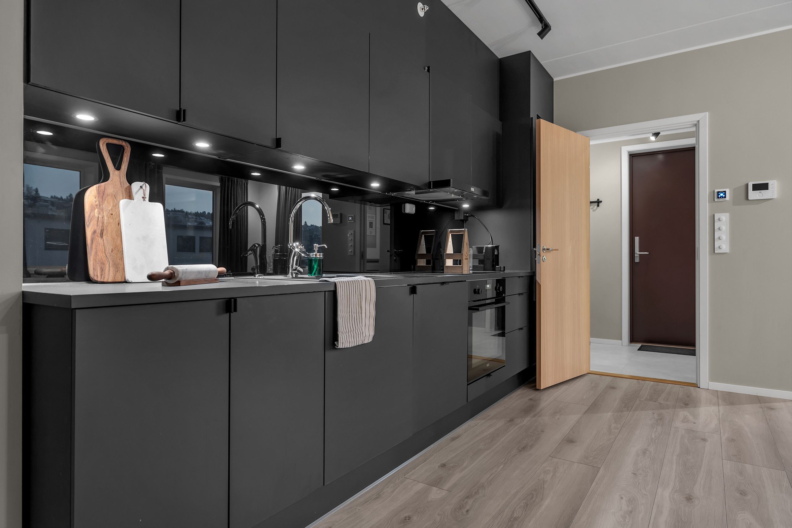 Een moderne keuken met donkere kastjes, een groot kookeiland en uitzicht op buiten.