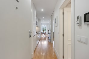 A modern hallway with a wooden floor, white walls, and a dining area in the background. - Apartment 'Almada Prime with Balcony' (Porto)