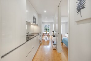 A modern kitchen with white cabinetry, a stainless steel sink, and a built-in oven. - Apartment 'Almada Prime with Balcony' (Porto)