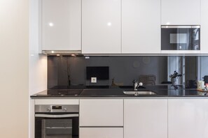 A modern kitchen with a built-in oven, a microwave, and a sink. - Apartment 'Cosy and Charming Almada Prime' (Porto)