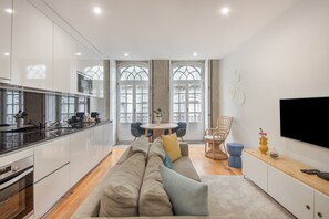 A modern kitchen with a dining area, a sofa, and a TV. - Apartment 'Cosy and Charming Almada Prime' (Porto)