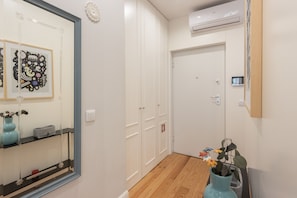 A hallway with a wooden floor, a white door, and a wall-mounted air conditioning unit. - Apartment 'Cosy and Charming Almada Prime' (Porto)