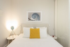 A hotel room with a bed, a bedside table, a lamp, and a framed picture on the wall. - Apartment 'Cosy and Charming Almada Prime' (Porto)