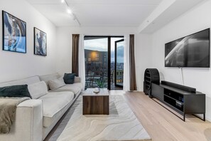 En moderne stue med sofa, sofabord, fjernsyn og kunst på væggene.
