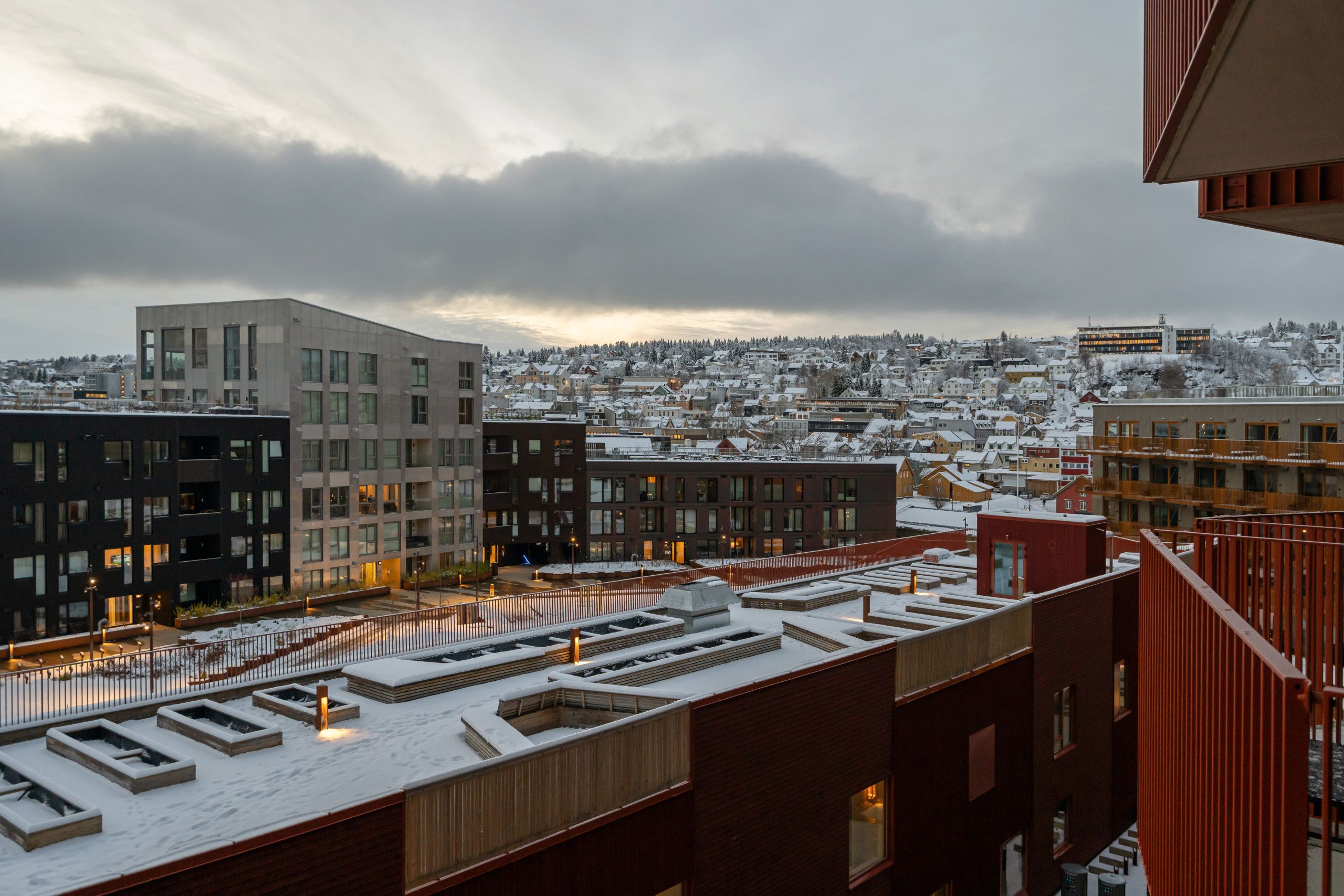A snow-covered urban landscape with modern buildings and a view of a residential area.