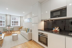 A modern kitchen with a microwave, oven, and a dining area with a table and chairs. - Apartment 'Enchanting Almada Prime' (Porto)
