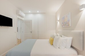 A bedroom with a bed, a flat-screen TV mounted on the wall, a door, and a painting. - Apartment 'Enchanting Almada Prime' (Porto)