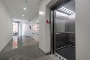 A hallway with lockers, a fire alarm, and an elevator. - Apartment 'Enchanting Almada Prime' (Porto)