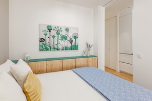 Ein Schlafzimmer mit einem Bett, einem Nachttisch, einem Wandbild und einem Holzschrank.