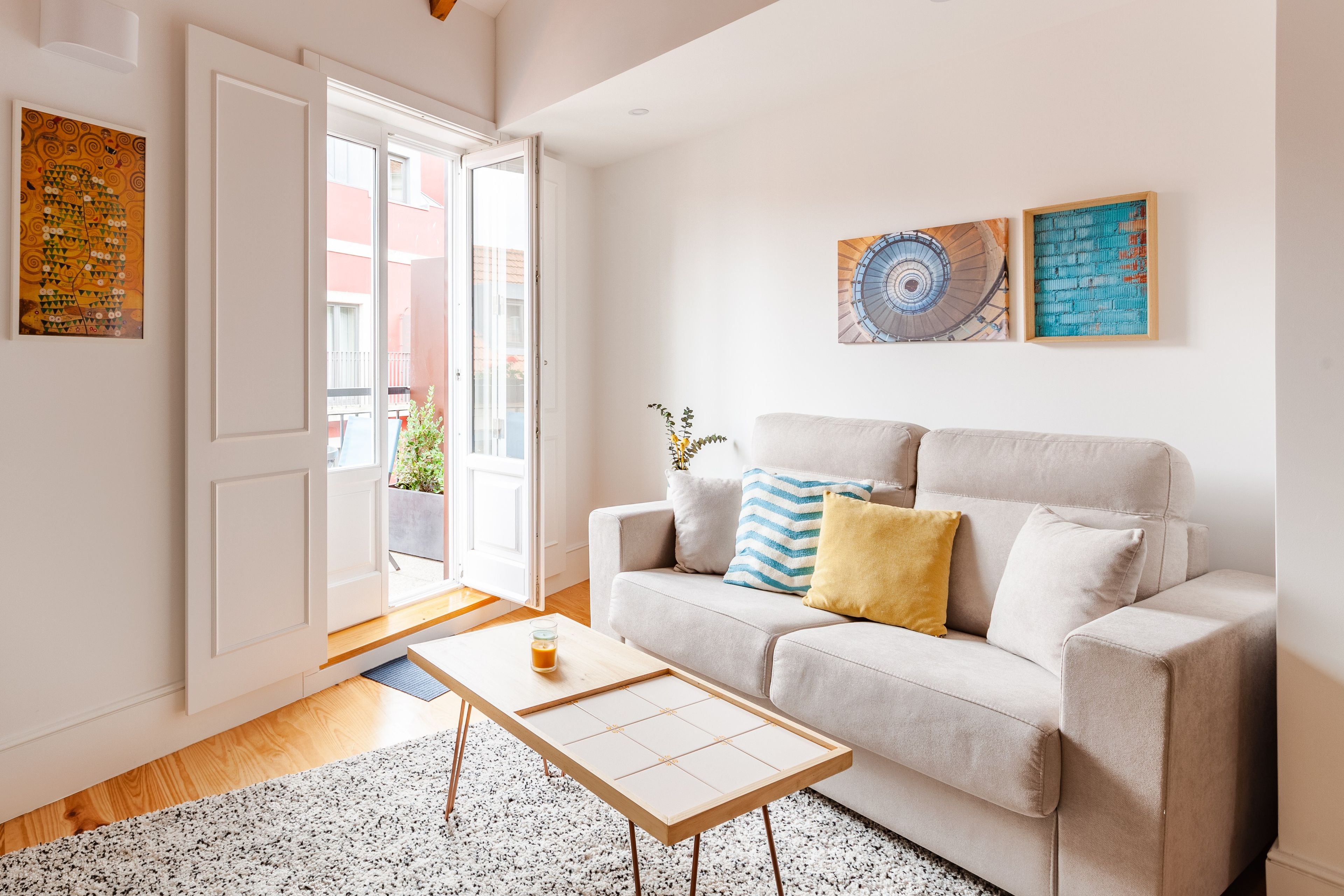 Una sala de estar con un sofá, una mesa de centro y una puerta que da a un espacio exterior.