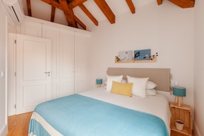 Ein Schlafzimmer mit einem Bett, Nachttischen, einem Wandbild und einer Holzzieldecke.