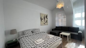 Ein modernes Schlafzimmer mit einem Bett, einem Sofa, einem kleinen Tisch und einem Wandbild.