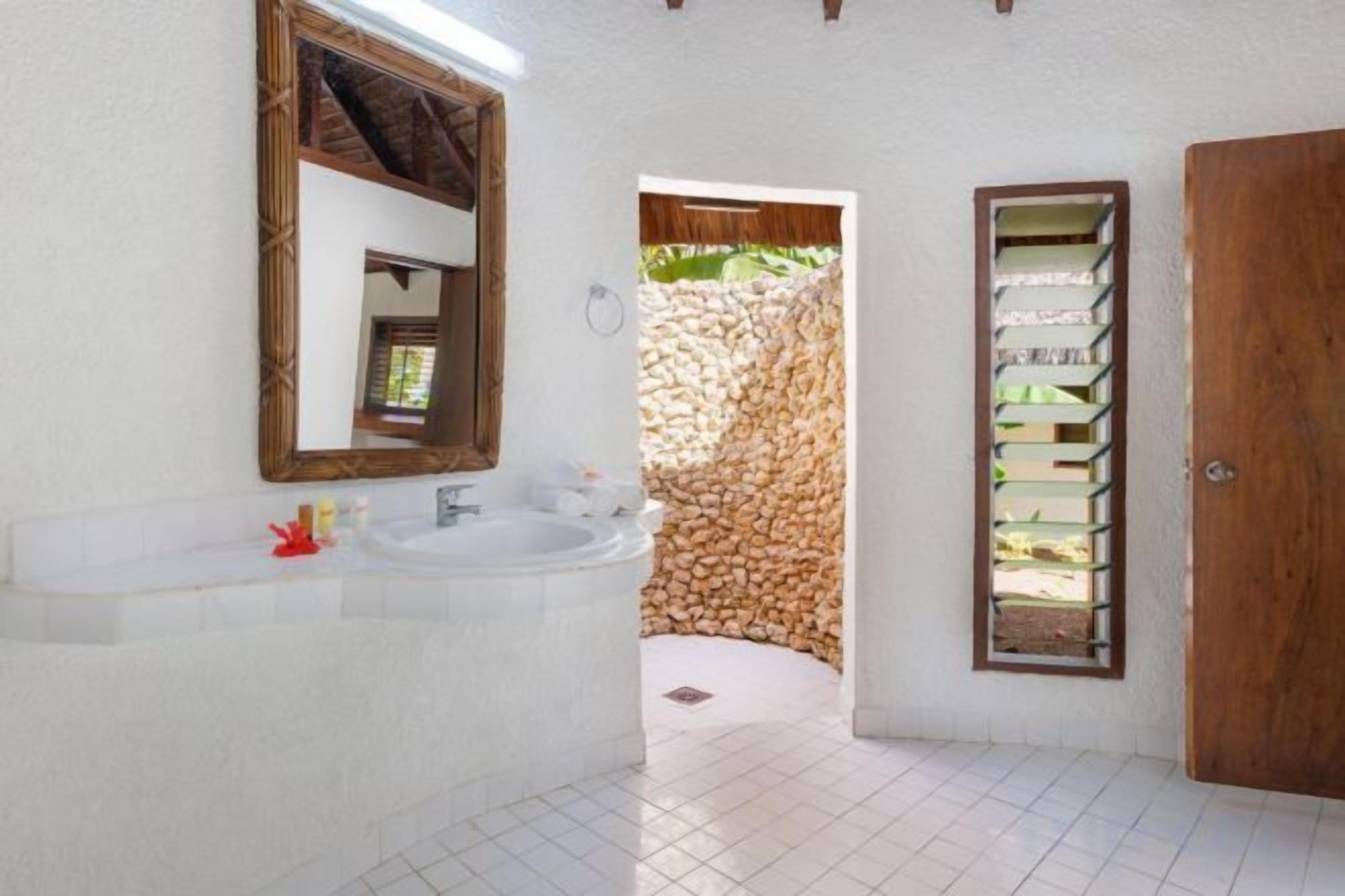 A bathroom with a white sink, mirror, and wooden door.