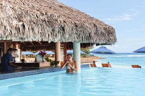 A poolside area with a thatched roof structure, lounge chairs, and a view of the ocean. - The Beach(formerly Breakas Beach Resort) (Efate)