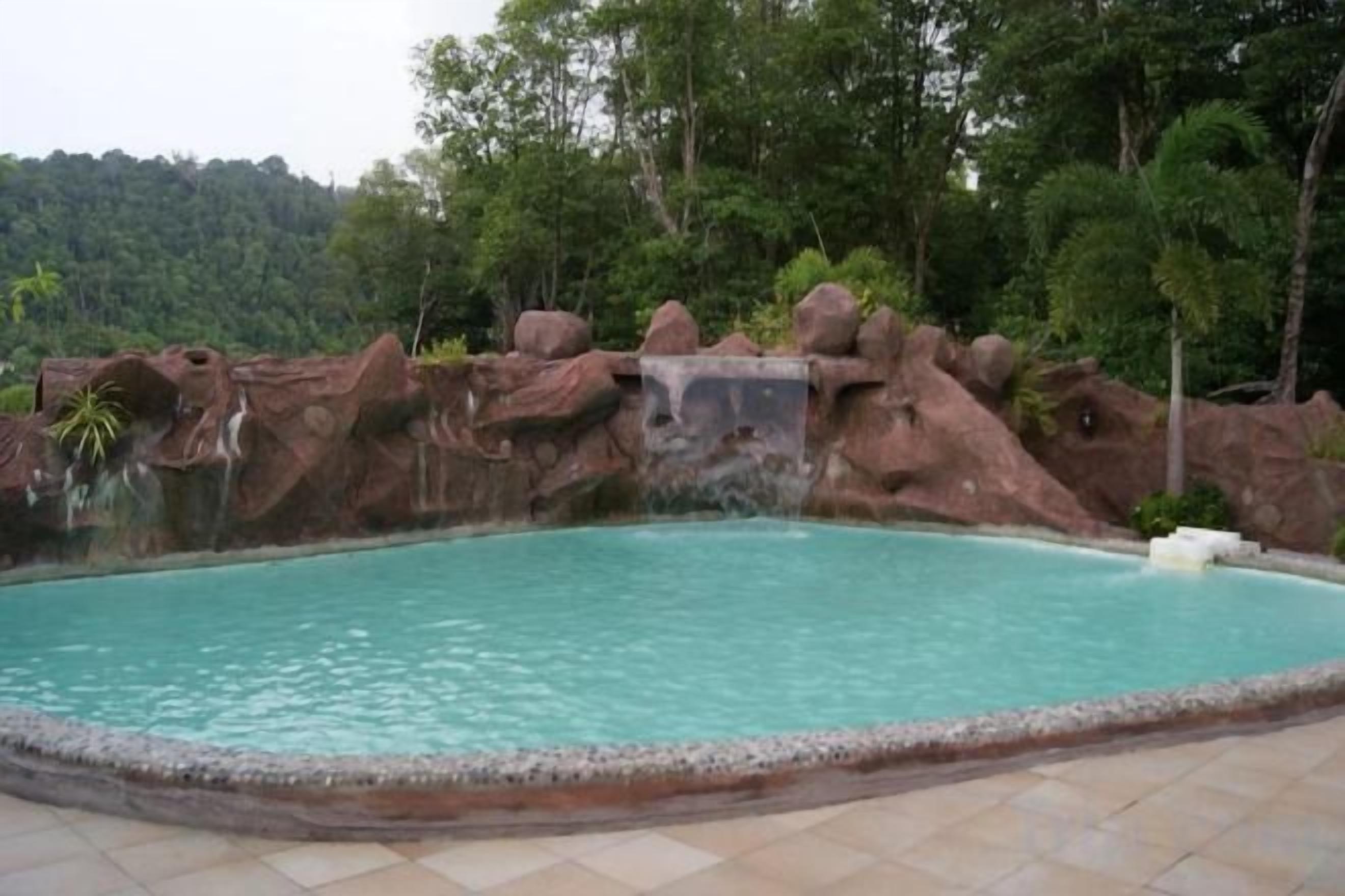 Ein Pool mit einer natürlichen Felsformation und einem Wasserfall.