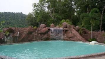 Ein Pool mit einer natürlichen Felsformation und einem Wasserfall.
