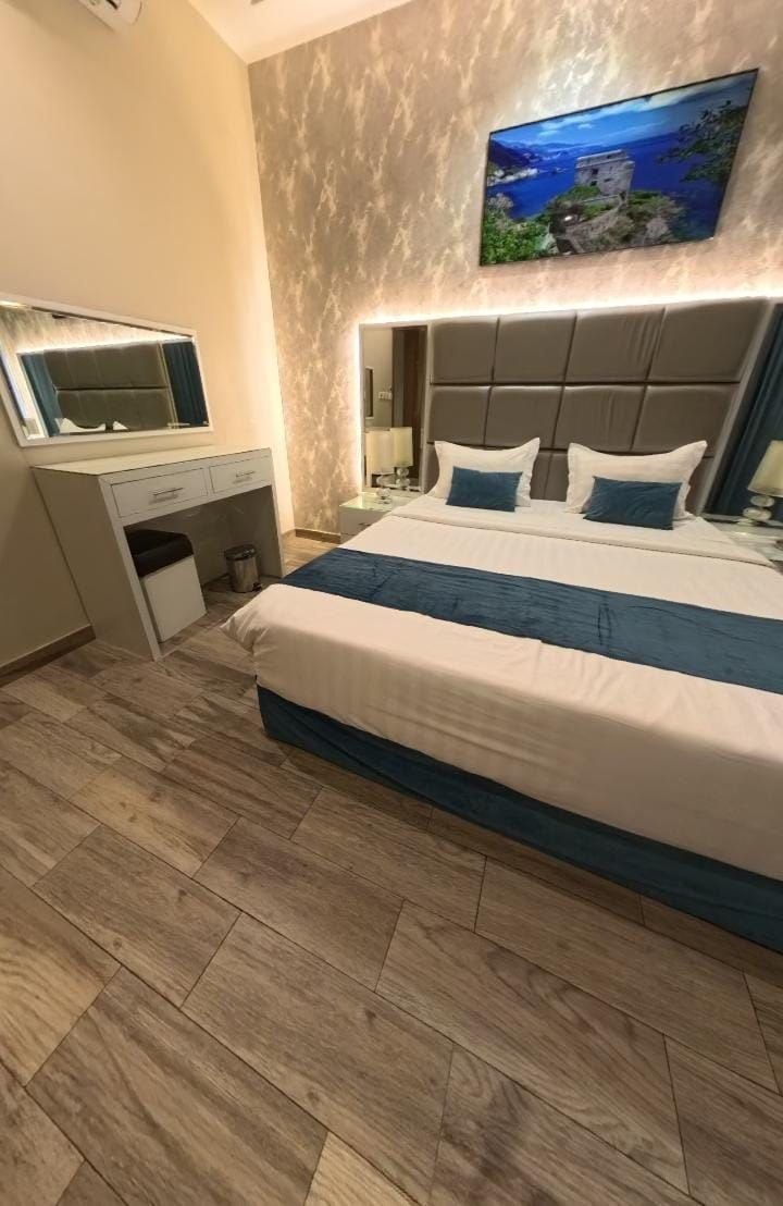 Habitación de hotel con cama, escritorio, espejo y televisor montado en la pared.
