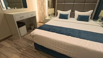 Habitación de hotel con cama, escritorio, espejo y televisor montado en la pared.