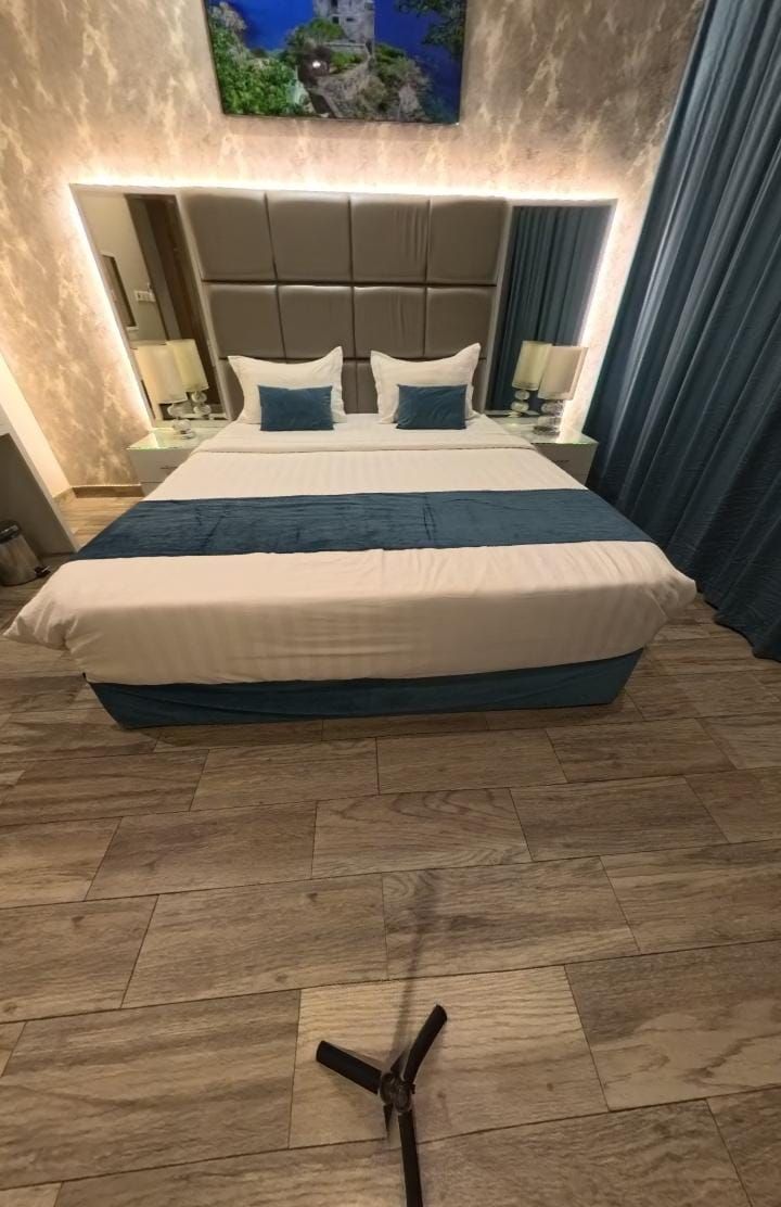 A hotel room with a large bed, a headboard, bedside tables, and a television mounted on the wall.