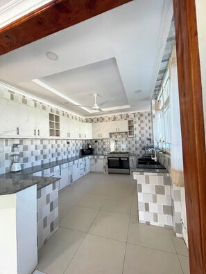 Une cuisine moderne dotée d’un îlot central, d’appareils électroménagers intégrés et d’un ventilateur de plafond.