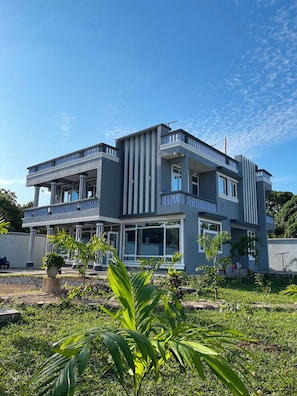 Une maison moderne à deux étages, dotée d’un balcon et entourée d’un jardin bien entretenu.