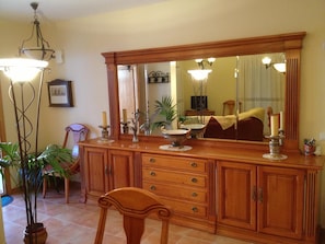 A dining area with a wooden cabinet, a mirror, and a chair. - Holiday Home 'Els Pins' with Private Terrace, Wi-Fi and Air Conditioning (Port d'Alcúdia)