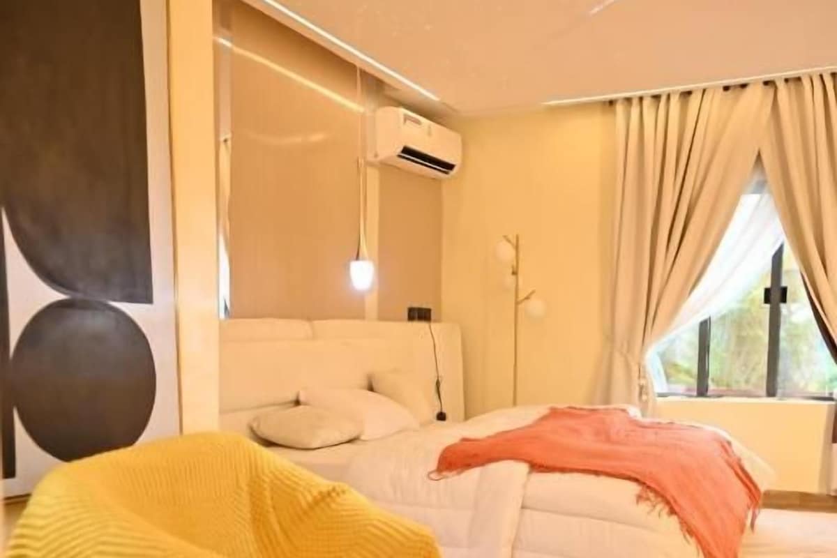A modern bedroom with a bed, a sofa, and a chair with a blanket.