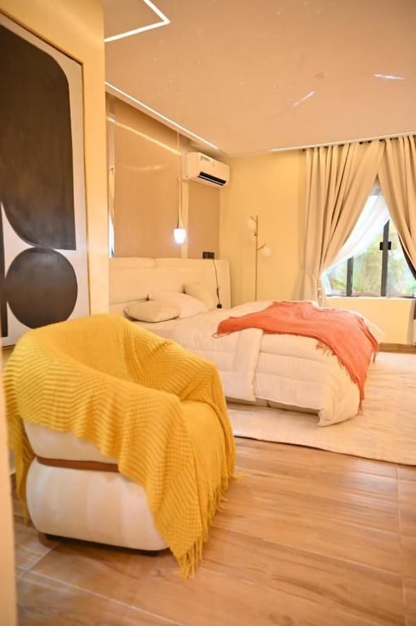 A modern bedroom with a bed, a sofa, and a chair with a blanket.