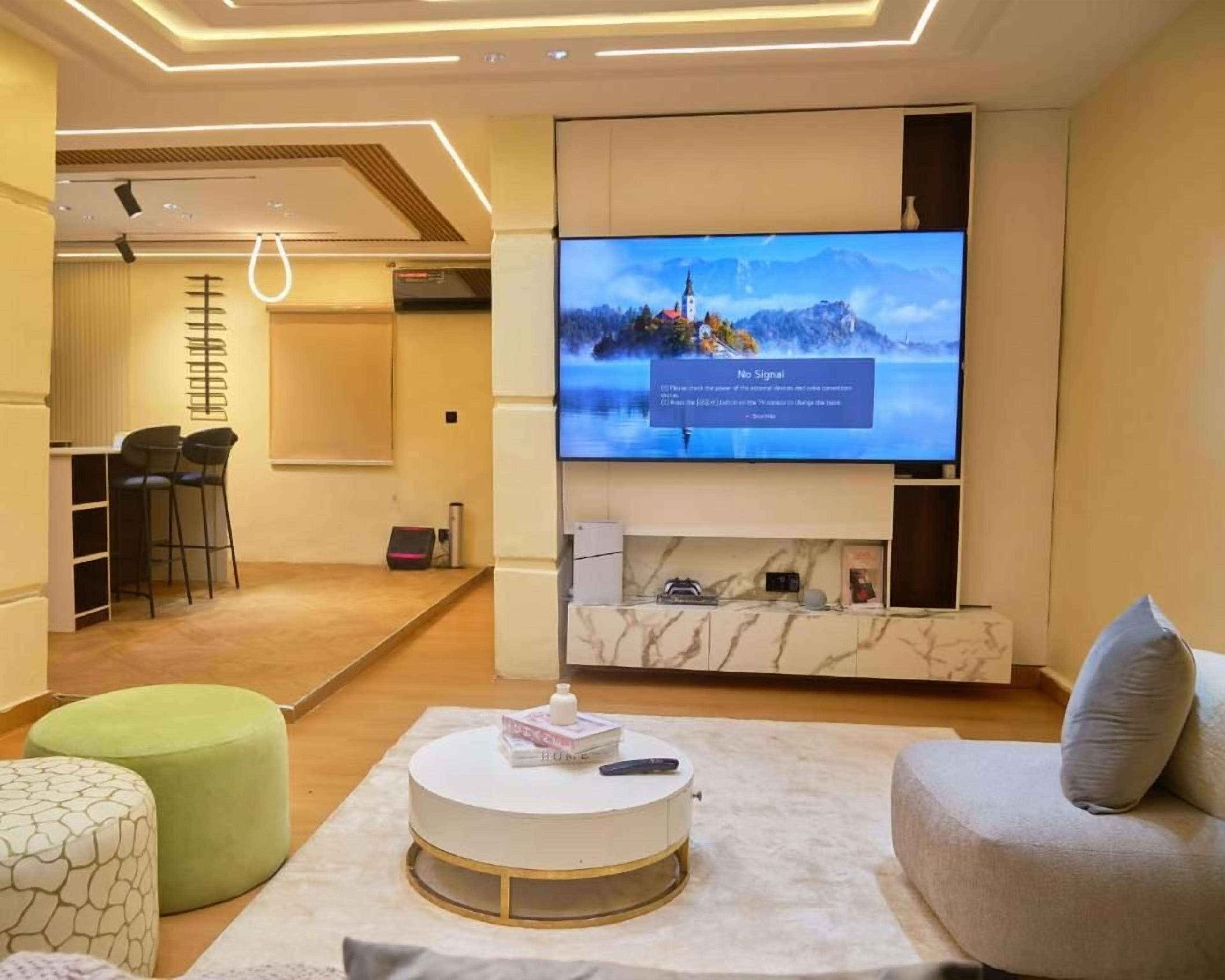 Una sala de estar moderna con un televisor de pantalla plana, una mesa redonda de centro y un sofá.