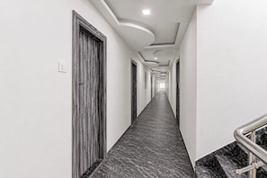 A long, narrow hallway with a marble floor and a modern ceiling design. - Hotel O Saibaba Temple Shirdi (Shirdi)