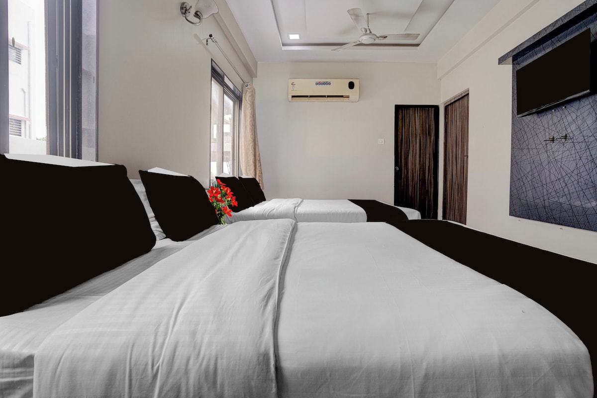 A hotel room with two beds, a ceiling fan, an air conditioning unit, and a window with curtains.