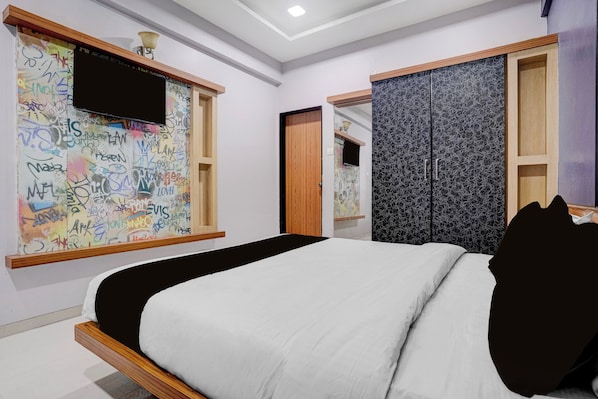 Une chambre à coucher avec un lit, un téléviseur fixé au mur et une armoire dont la porte est ornée d’un motif.