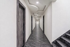 Un pasillo largo y estrecho con suelo de mármol y una escalera a la derecha.