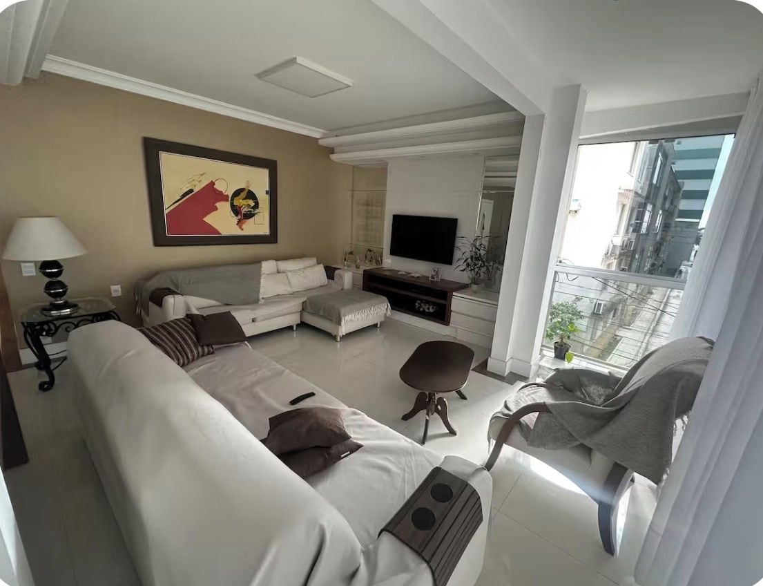 Uma sala de estar moderna com um sofá, poltrona e TV de tela plana.