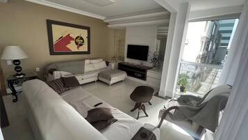 Uma sala de estar moderna com um sofá, poltrona e TV de tela plana.