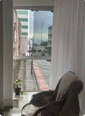 Una habitación con vista a la calle, una silla y una planta en maceta.
