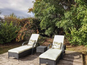 Zwei Lounge-Sessel mit Kissen, ein kleiner Tisch und eine Holzterrasse.