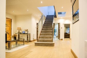 A spacious hallway with a carpeted staircase, a glass table with a lamp, and a door leading to another room. - Luxury6 Bed Villa-HotTub-FootballPitch-DogFriendly (Poole)
