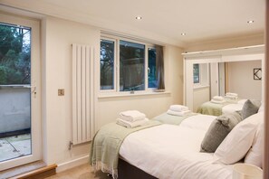 A bedroom with two beds, a window, a radiator, and a mirror. - Luxury6 Bed Villa-HotTub-FootballPitch-DogFriendly (Poole)