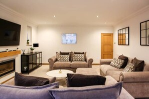 A living room with a fireplace, two sofas, a coffee table, and a TV. - Luxury6 Bed Villa-HotTub-FootballPitch-DogFriendly (Poole)