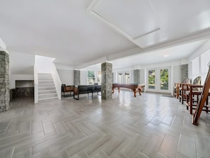 A spacious living area with a herringbone floor pattern, a pool table, and a fireplace. - Two-story 3BR With Pool Table and Private Yard (St. Petersburg)