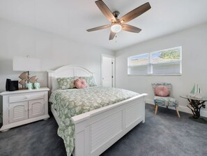 A bedroom with a bed, a nightstand, a chair, a ceiling fan, and a window. - Two-story 3BR With Pool Table and Private Yard (St. Petersburg)