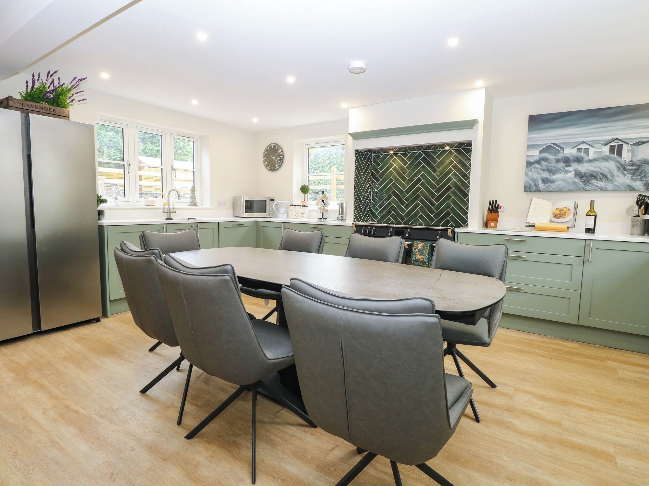 A modern kitchen with a dining table, chairs, and a refrigerator.