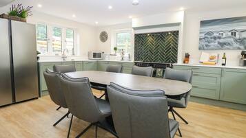 A modern kitchen with a dining table, chairs, and a refrigerator.
